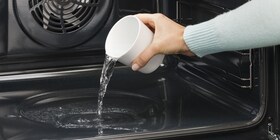 Човек налива вода в кухината на фурната