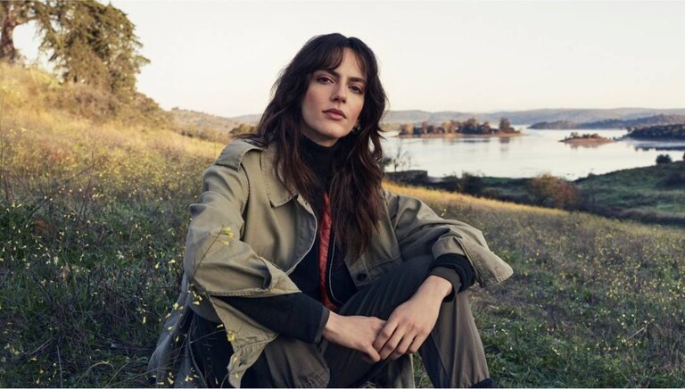 Жена, седнала на тревата сред природата.